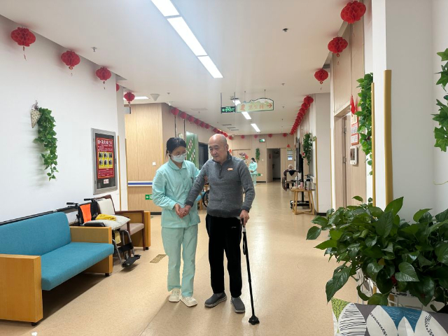 护理员乔瑞霞正在辅助入住中心的全托老人行走.jpg